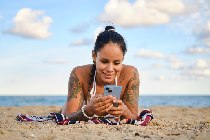 Young woman relaxing on the beach using smartphone
