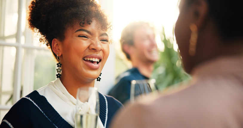 Party, woman laughing and drinking wine with friends, talking and reunion at new year event. Champagne glass, girl and group at celebration for social gathering, funny joke and holiday at restaurant