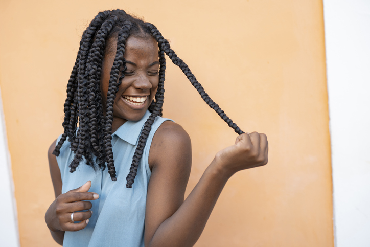 Portrait of teenage afro girl with braided hair on orange background