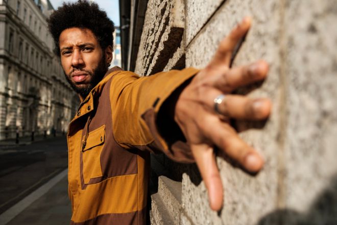 Stylish man posing with hand on a wall in the city