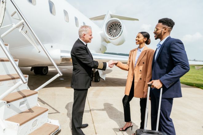 Passengers arriving in private luxury jet near hangar, pilot welcomes the young successful passengers