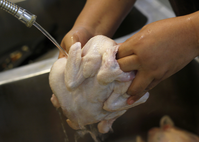 Unrecognizable Hand Washing Raw Chicken in Kitchen Sink
