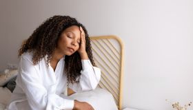 Young woman suffering from headache sitting on bed