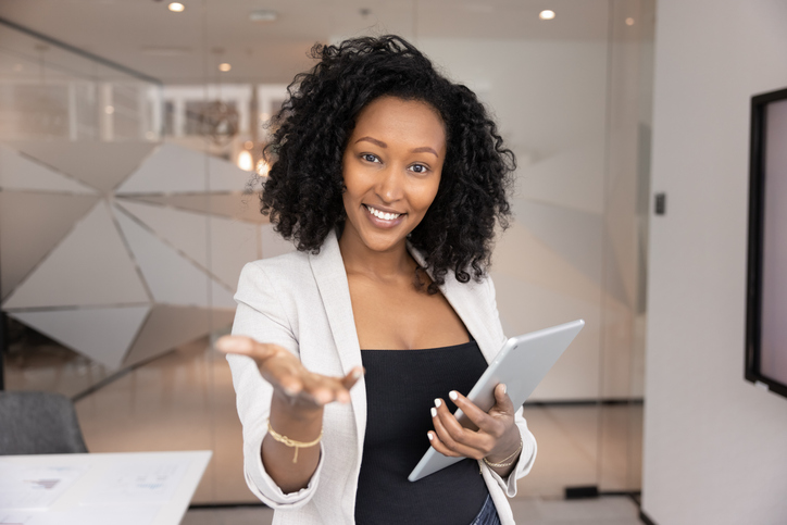 Smiling African businesswoman greeting client, extends her arm for handshake