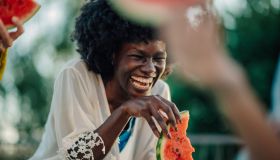 Young woman laughing while eating watermelon slice at a summer party