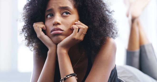 Depression, sad and thinking with woman in bedroom of home for breakup or unhappy memory. Anxiety, burnout and mental health with miserable, moody or thoughtful African person on bed in apartment