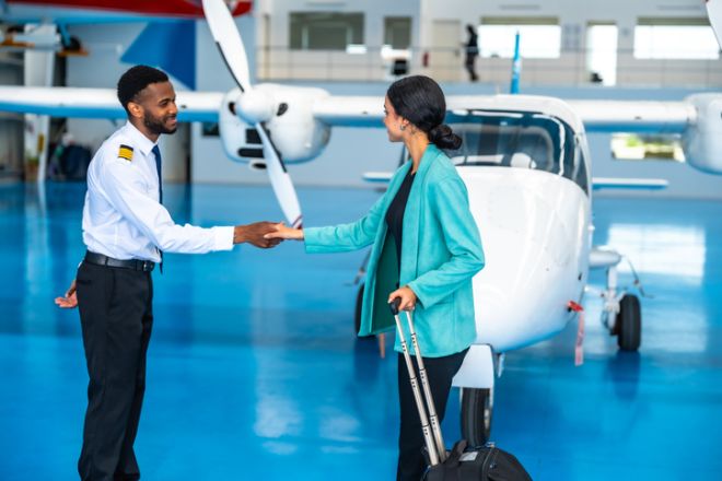 Pilot shaking hands with businesswoman boarding private plane