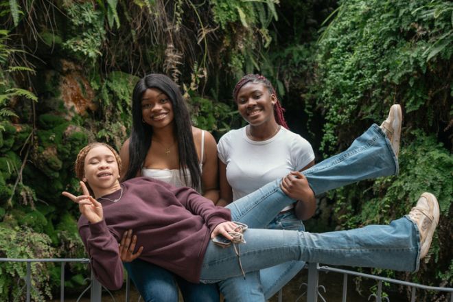 Three playful teen friends having fun in a botanical garden
