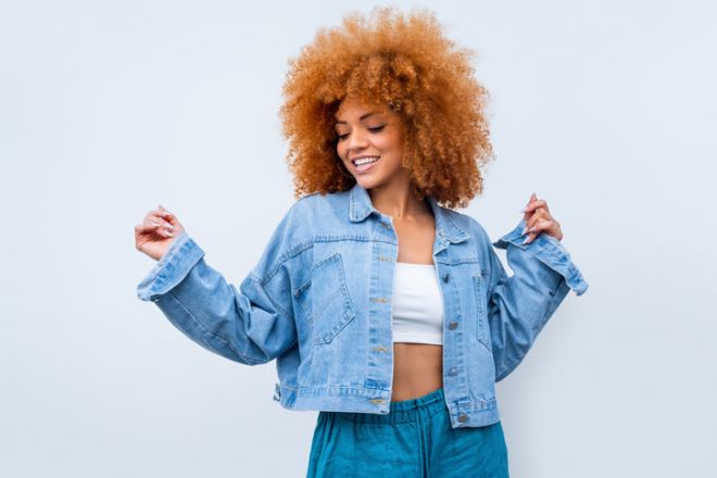Happy young African American woman dancing and jumping on yellow background