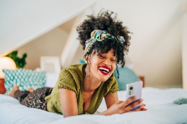Woman using the mobile phone in the bed at home.