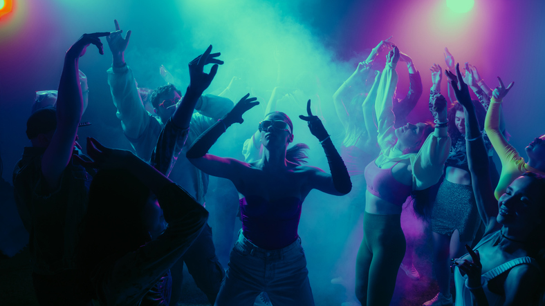 A vibrant party scene with diverse people dancing under colorful lights.