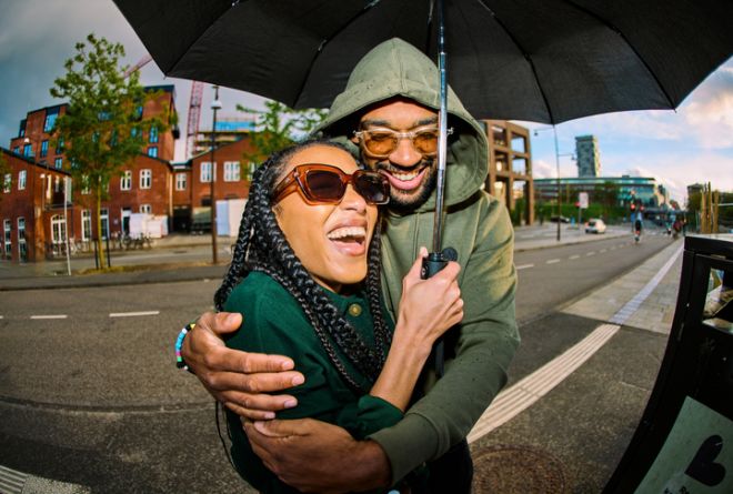 Young couple sharing umbrella and laughing in the city