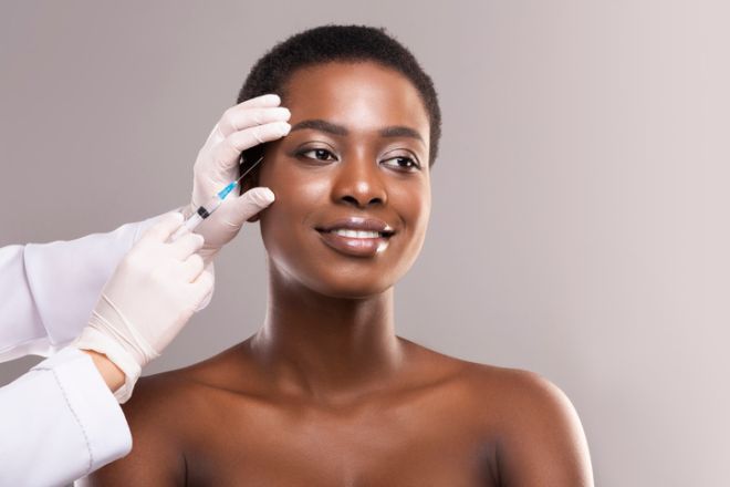 Young black woman getting beauty injection under skin