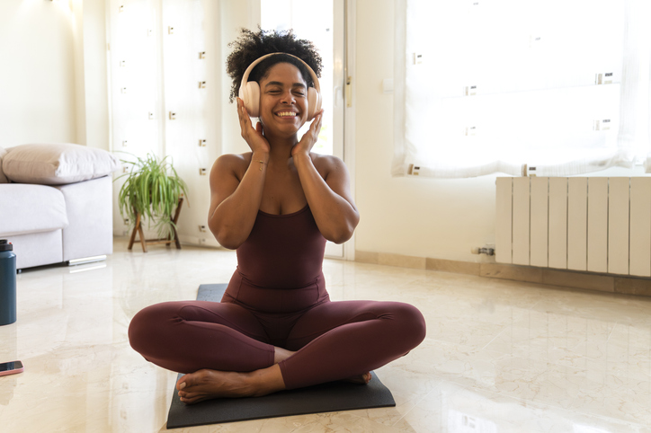 Happy woman meditating with headphones at home