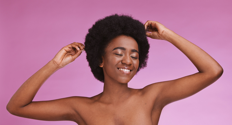 Black woman, touching afro hairstyle on beauty studio background in relax skincare, texture maintenance or salon wellness. Model, natural and hair growth hands on isolated pink or makeup backdrop