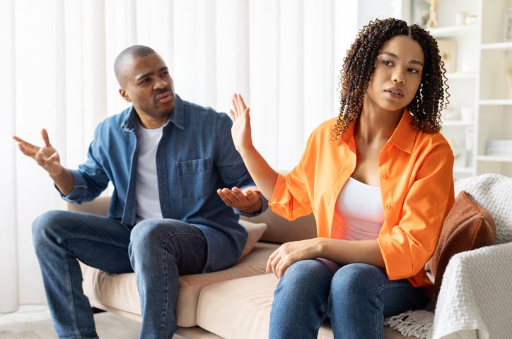 African American couple arguing at home, woman turning away with protest