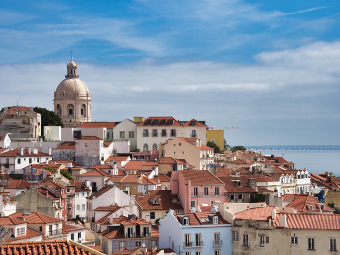 Domed Church and Alfama Rooftops in Lisbon, Portugal - High-angle view of the dense, historic Alfama district featuring terracotta rooftops with the National Pantheon dome prominent on the skyline.