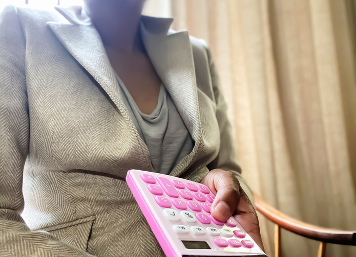 african-american woman holds pink calculator at desk