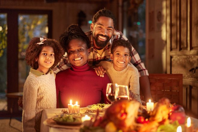 Happy black family enjoying during Thanksgiving dinner at dining table.
