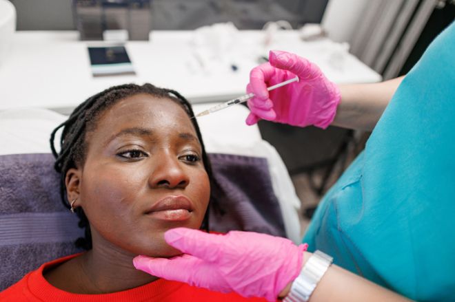 Beautician Administering Botox Injection to Black Female Patient