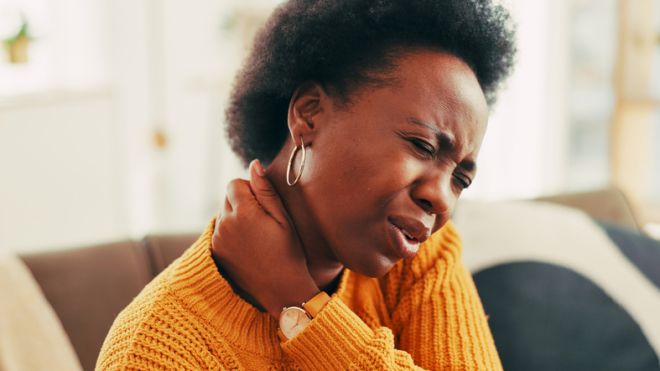 Black woman, discomfort and neck pain on couch at house of joint inflammation, spine accident and relief. Person, massage muscle and wrong posture, nerve pressure and sore shoulder for burnout injury