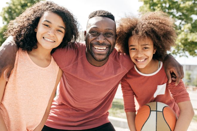 Dad and daughters posing with basketball ball