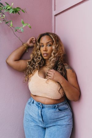 Woman Leaning Against Pink Wall in Casual Outfit