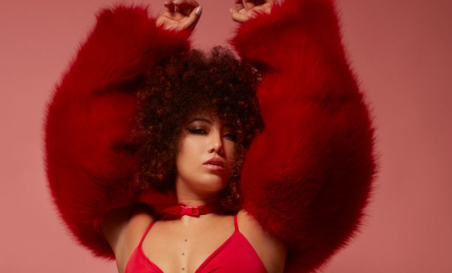 Curly-haired mixed race young woman in a red fur coat.