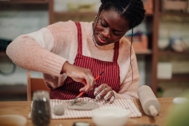 Woman creating pottery product with clay in workshop