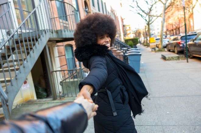 Smiling woman holding hand leading on new york city street