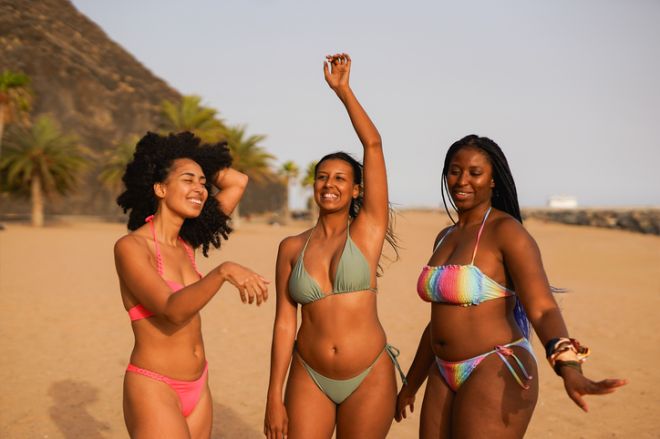 Young multiracial women dancing together on the beach during summer vacation - Holiday, diverse people and party concept