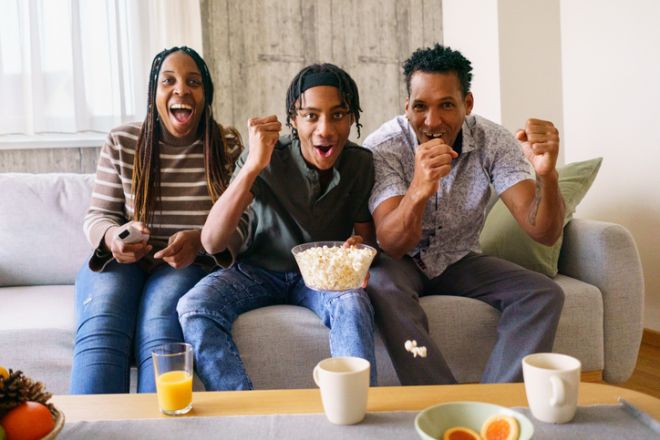 African American family feels delighted as they watch television together.