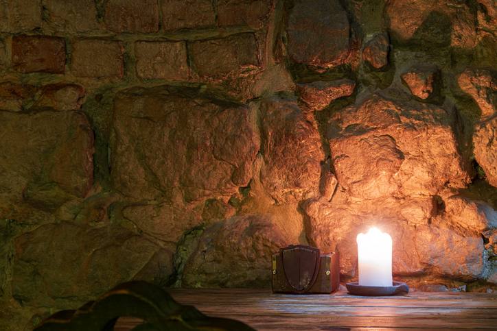 dungeon tavern cave candle light on a table and cold stone wall background dark twilight low key condition antique interior space
