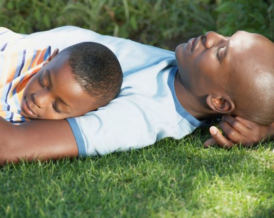 Father and son (5-7) asleep on grass, close-up