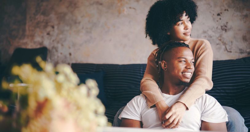 Thinking, couple and hug in lounge, trust and bonding on break with smile, love and romance in home. Happy, man and embrace with woman in living room, affection and reflection for future in house