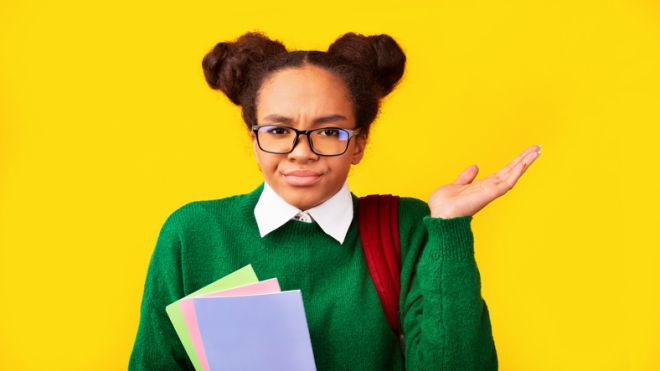 Afro teenager spreading hands on yellow background