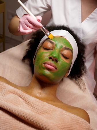 Black Woman Getting Green Facial Mask in Spa