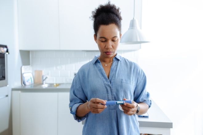 Happy woman preparing insulin injection in modern kitchen at home