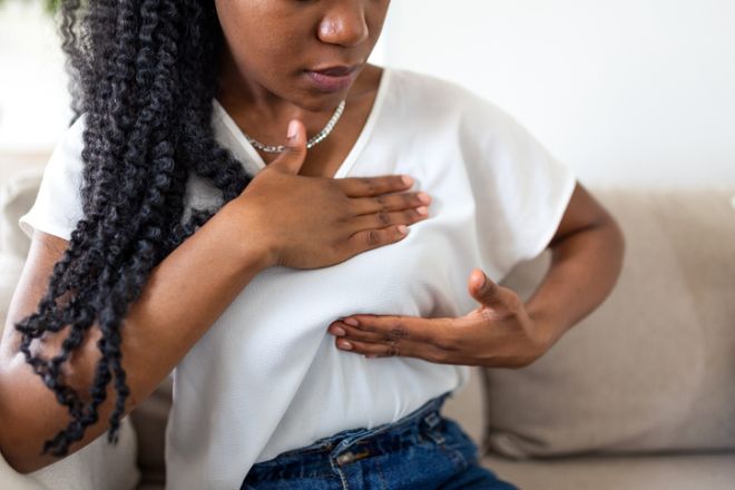 Breast self-examination. African American woman checking for lumps, People with breast cancer problem, Healthcare And Medicine concept. Black female sitting on sofa and touching breast for health.