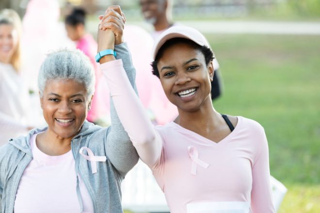 Two women with pink ribbons celebrating participation in a breast cancer awareness walk.