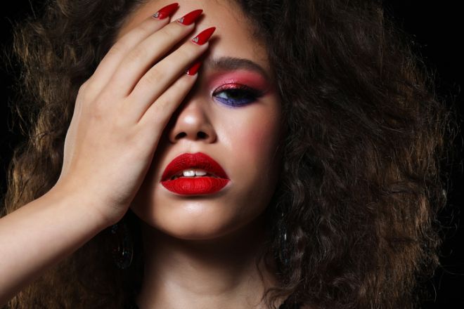 Smiling dreamy beautiful black woman covers her eyes with her palm