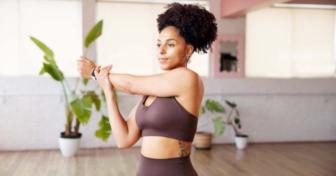 Fitness, woman and stretching arms in studio for wellness, health and start yoga. African person, yogi and warm up at club for pilates preparation, flexibility and getting ready to exercise muscle