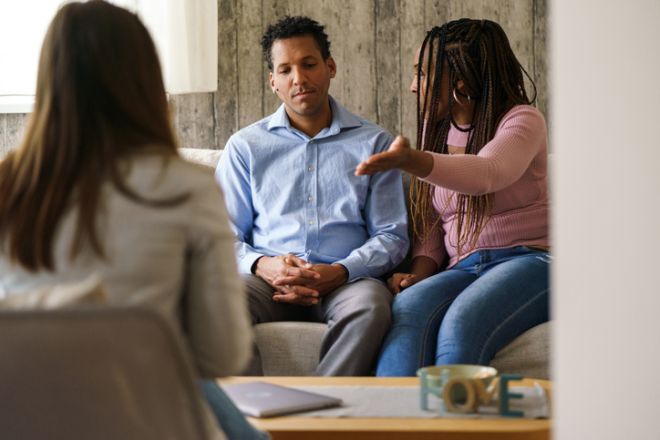 Couple discussing problems during counseling session with therapist.