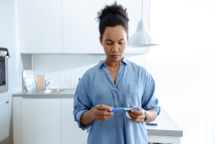 Happy woman preparing insulin injection in modern kitchen at home