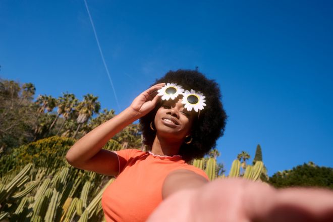 Young black woman wearing flower sunglasses taking selfie