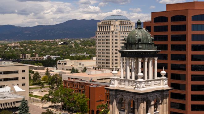 Historic Courthouse with copper dome overlooking downtown Colorado Springs. Morning cityscape with mountain backdrop and commercial district.
