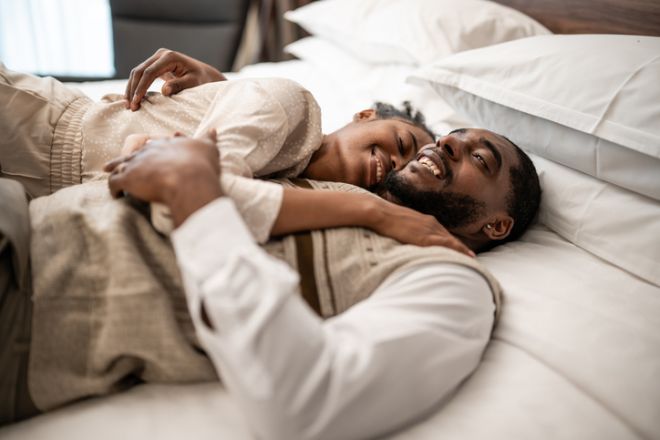 Young couple embracing and smiling lying in bed