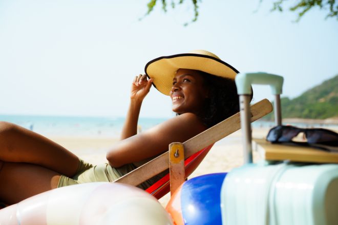 Happy black woman relaxing in deck chair on sunny beach vacation