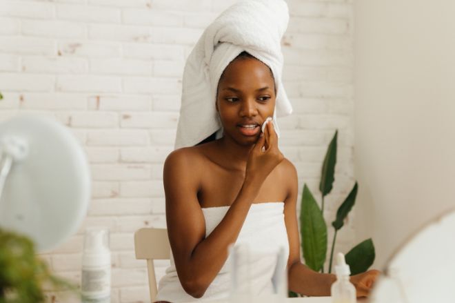 Woman cleaning face with cotton pad at home