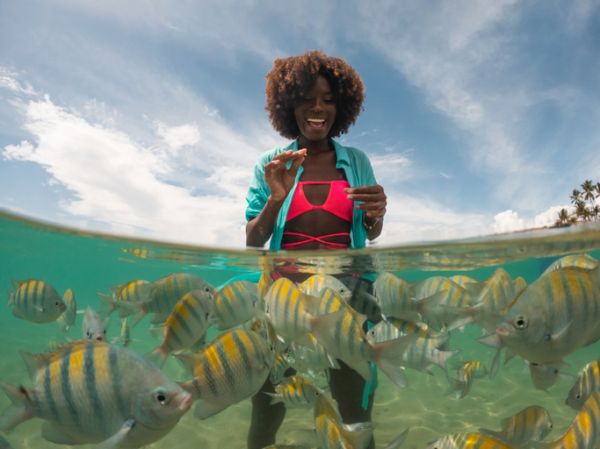 Afro teenage girl feeding fish on Porto de Galinhas beach